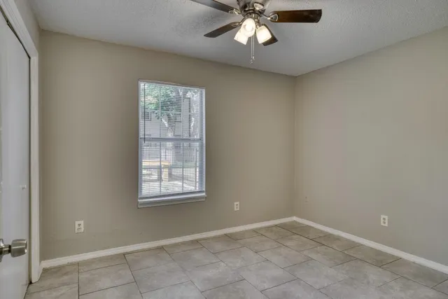 an empty room with windows and fan