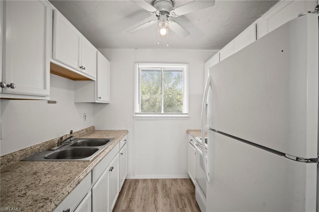 3215 Jeffcott Street Fort Myers, FL 33916 - Photo 14 of 33 Kitchen featuring freestanding refrigerator, light wood-style floors, white cabinets, a ceiling fan, and light countertops