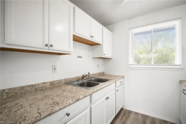 a kitchen with granite countertop white cabinets and a sink