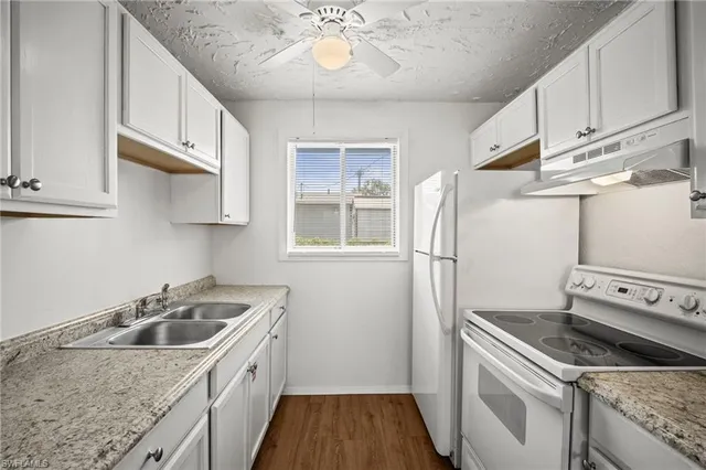 a kitchen with granite countertop white cabinets and sink