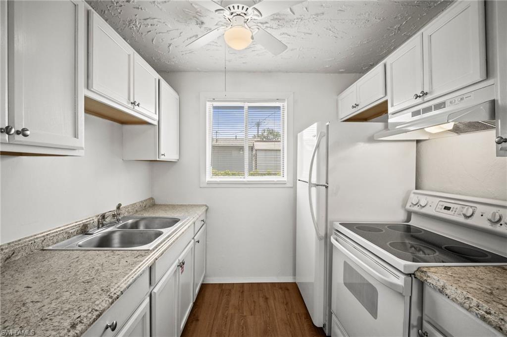 3215 Jeffcott Street Fort Myers, FL 33916 - Photo 24 of 33 Kitchen with white electric range, under cabinet range hood, dark wood finished floors, ceiling fan, and white cabinetry