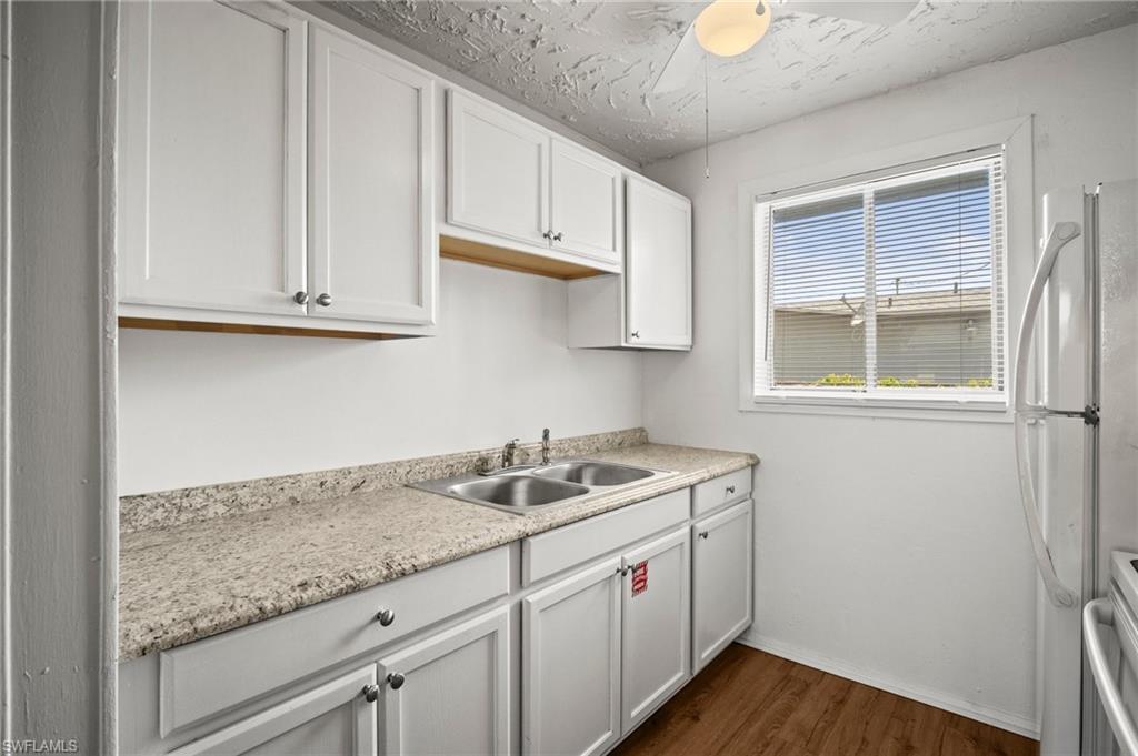 3215 Jeffcott Street Fort Myers, FL 33916 - Photo 25 of 33 Kitchen featuring freestanding refrigerator, dark wood-style flooring, light countertops, and white cabinets