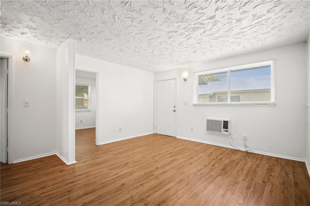 3215 Jeffcott Street Fort Myers, FL 33916 - Photo 3 of 33 Unfurnished living room with a wall unit AC, wood finished floors, and a textured ceiling