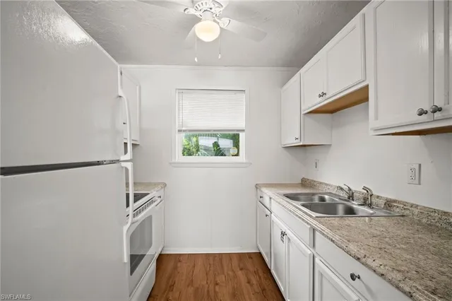 a kitchen with stainless steel appliances granite countertop a refrigerator a sink dishwasher a stove and white countertops with wooden floor