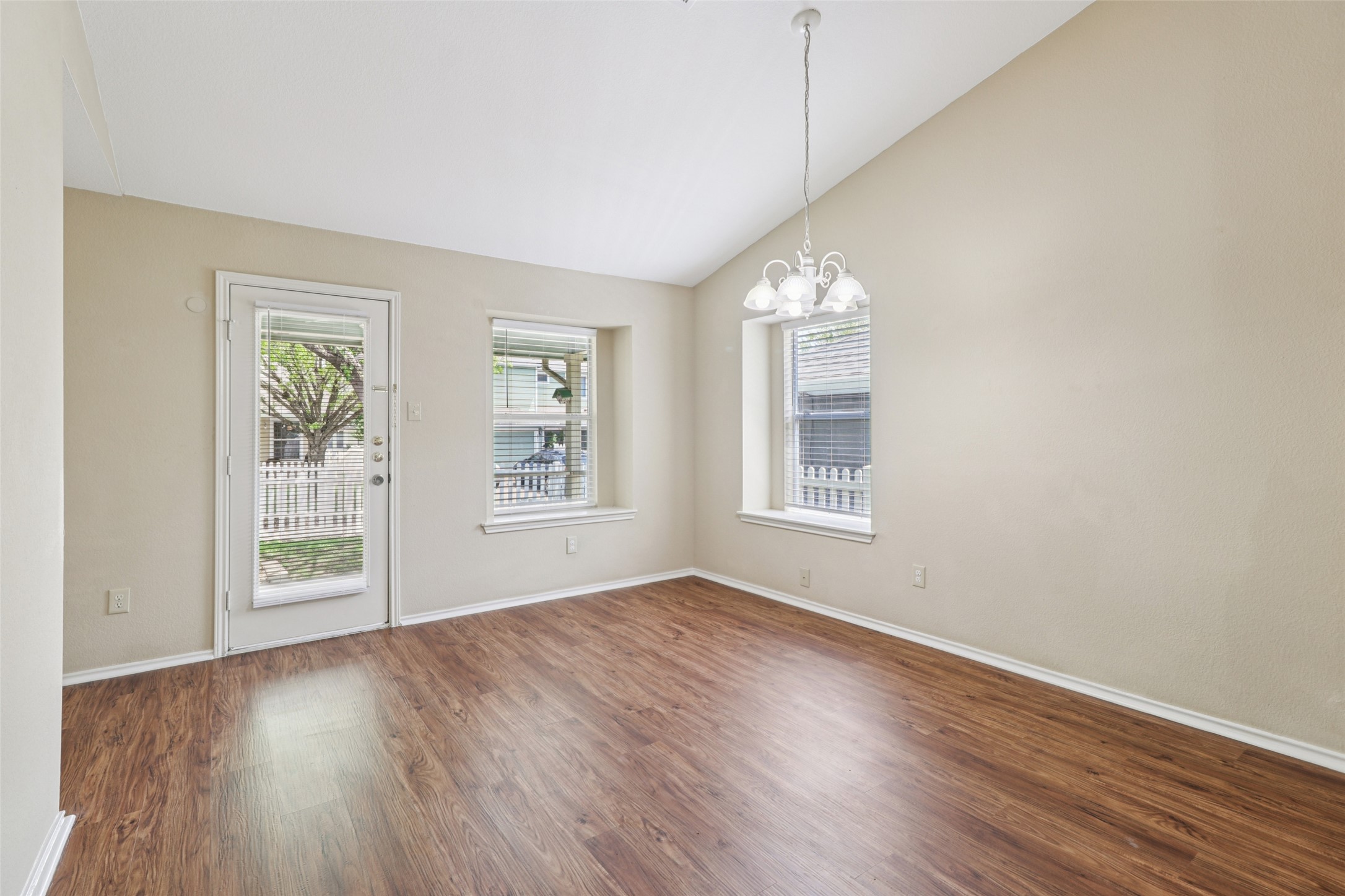 700 Scheel Road Kyle, TX 78640 - Photo 12 of 39 The property features high vaulted ceilings, durable wood-look flooring, and a glass-paneled door leading to an outdoor area