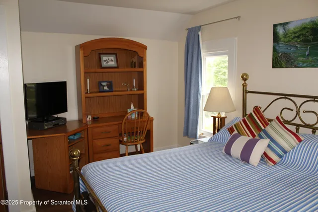 a bedroom with a bed and a flat tv screen on dresser