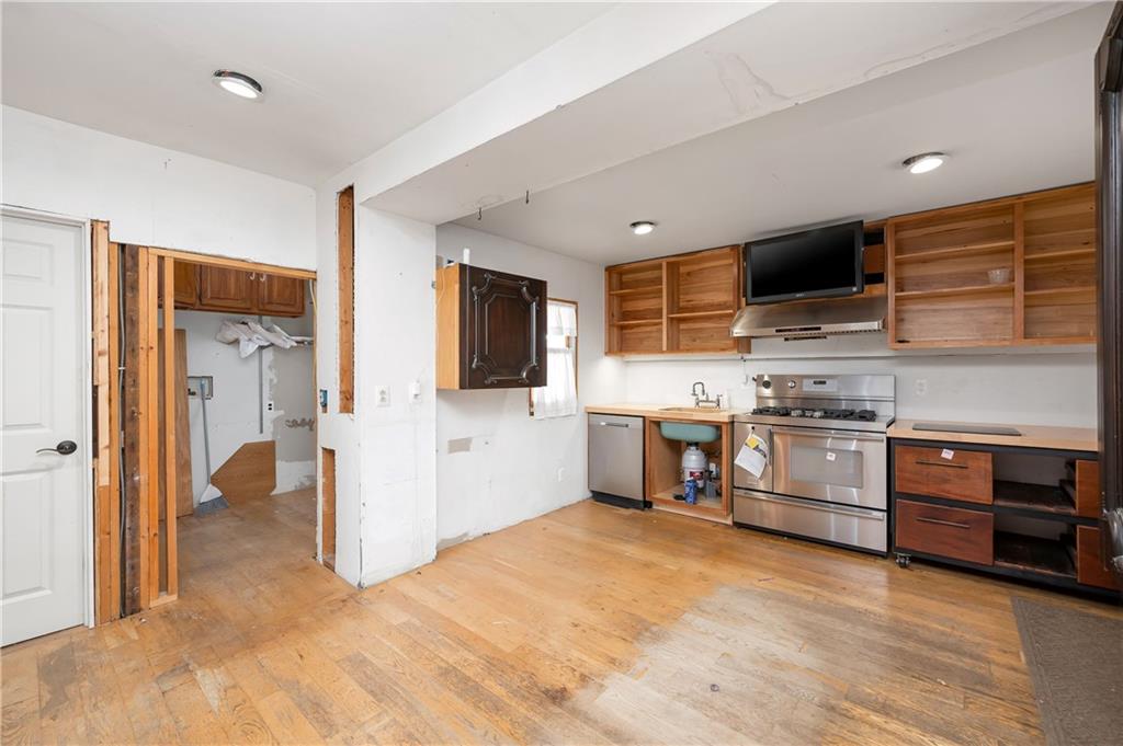438 Main Street Prospect, PA 16052 - Photo 11 of 46 a kitchen with stainless steel appliances kitchen island granite countertop a stove top oven a sink dishwasher a dining table and chairs with wooden floor