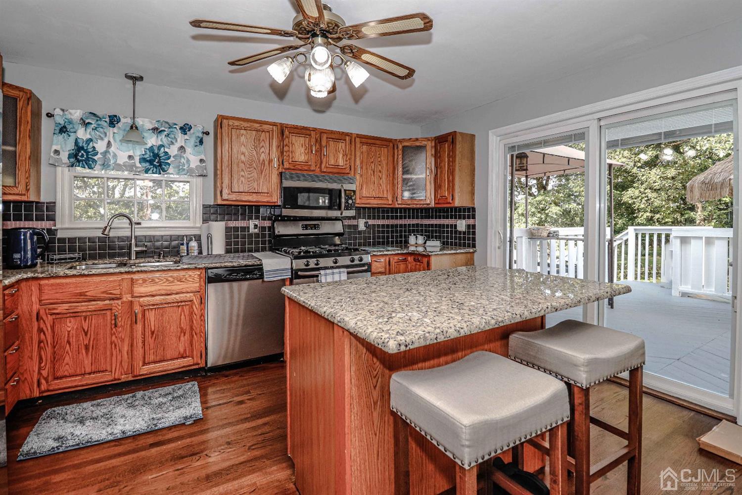 12 Bowser Road New Brunswick, NJ 08901 - Photo 5 of 21 a kitchen with stainless steel appliances granite countertop a stove top oven a sink dishwasher a dining table and chairs with wooden floor
