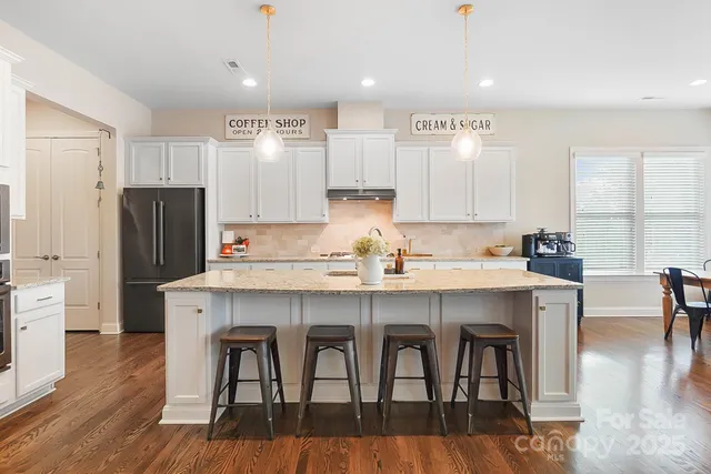 a kitchen with stainless steel appliances granite countertop a dining table chairs refrigerator microwave and cabinets