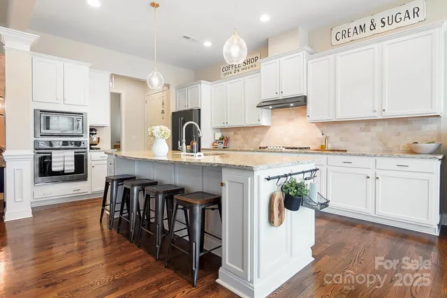 a kitchen with stainless steel appliances granite countertop a white cabinets and wooden floor