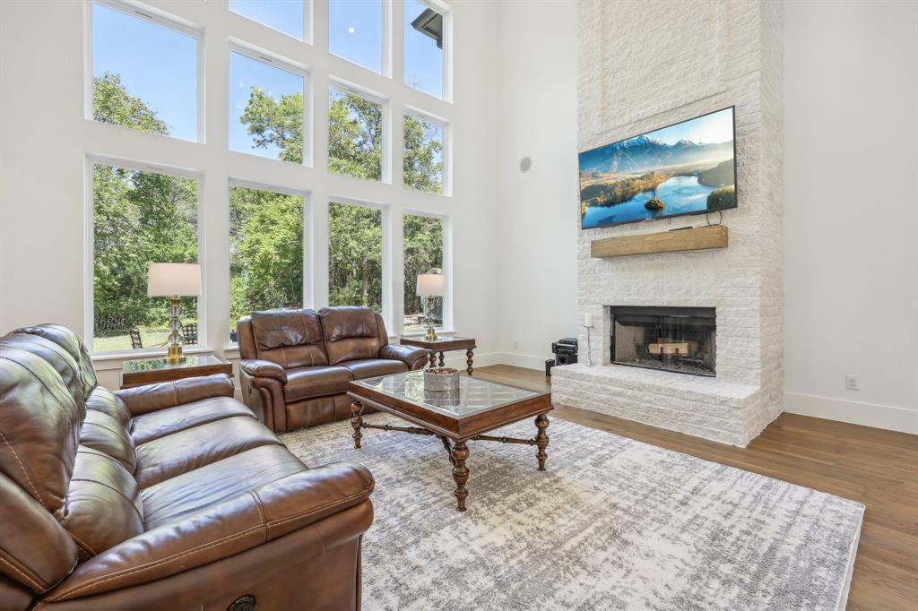 478 Polly Road Sunnyvale, TX 75182 - Photo 9 of 40 Living area with plenty of natural light, a towering ceiling, a stone fireplace, and wood finished floors