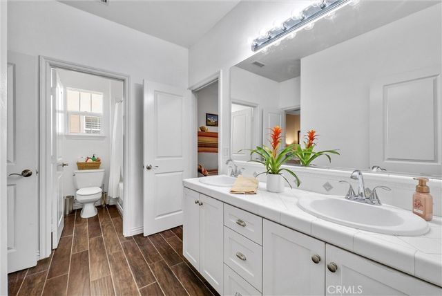 a bedroom with a bed a dresser and potted plants