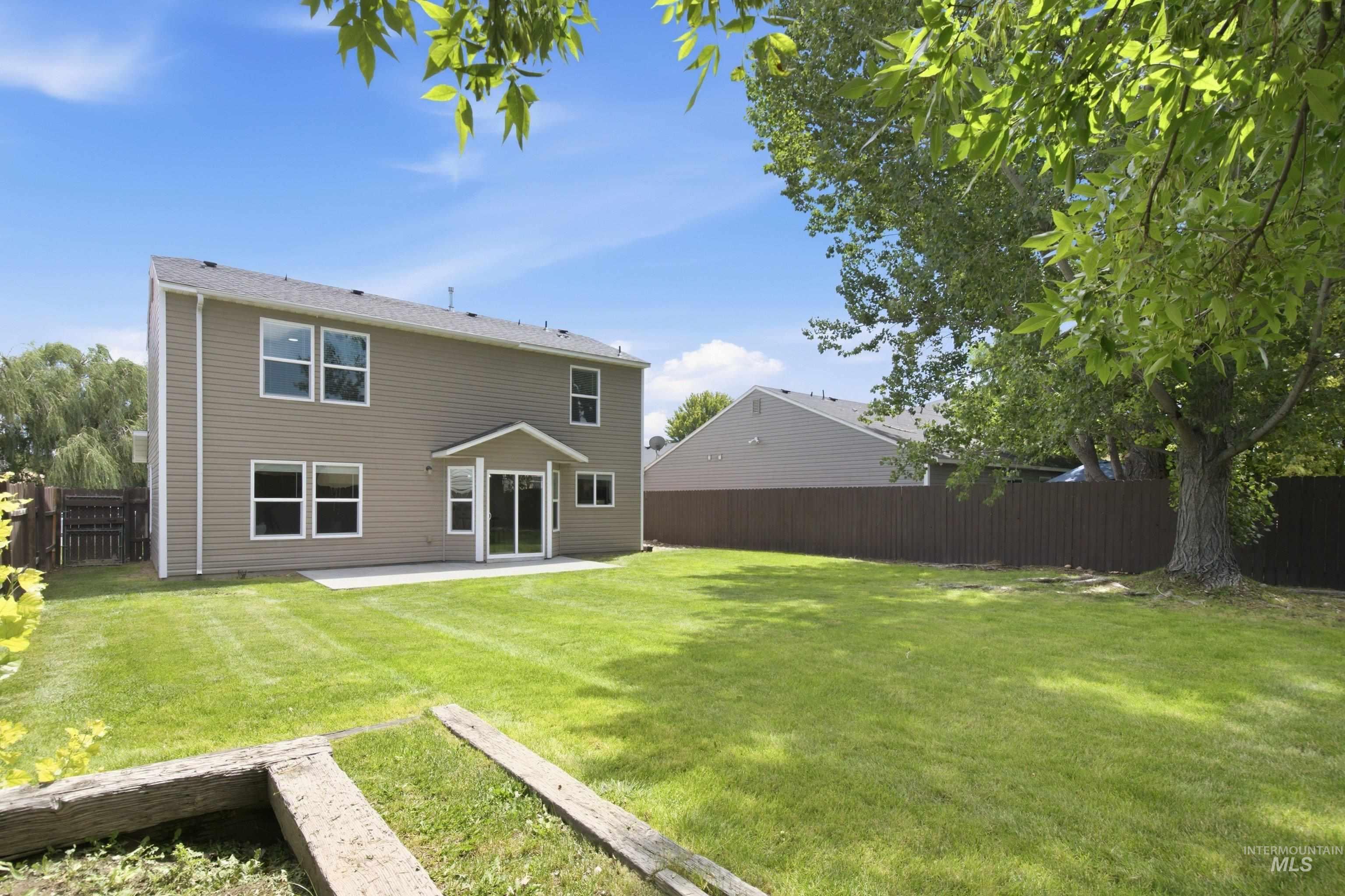16759 Abram Avenue Caldwell, ID 83607 - Photo 27 of 33 Expansive backyard featuring a large green lawn, mature trees, and a concrete patio