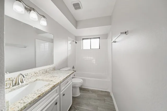 a bathroom with a granite countertop sink a toilet and shower