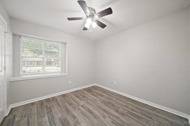 an empty room with wooden floor and windows