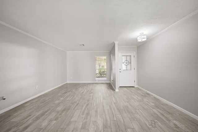 a view of an empty room with window and wooden floor