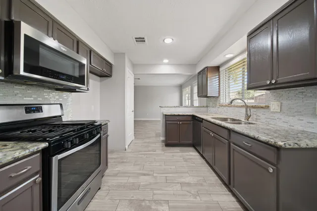 a kitchen with stainless steel appliances granite countertop a stove microwave and sink