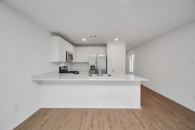 a view of kitchen with stainless steel appliances granite countertop a sink a stove and a wooden floors