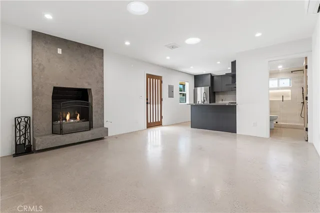 an empty room with kitchen view and a refrigerator