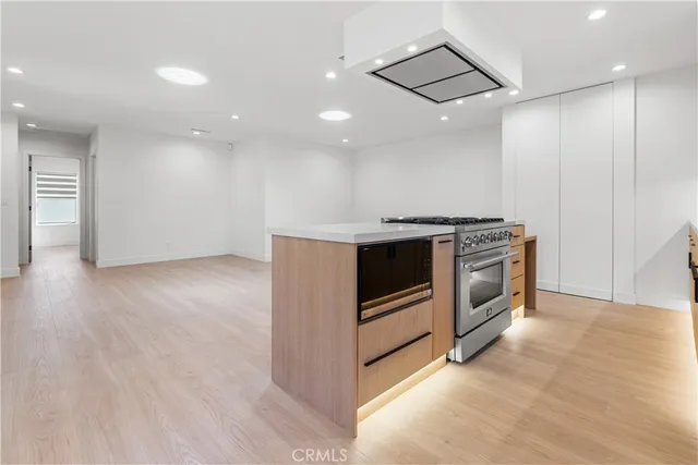 a view of a kitchen with a stove wooden cabinets and wooden floor