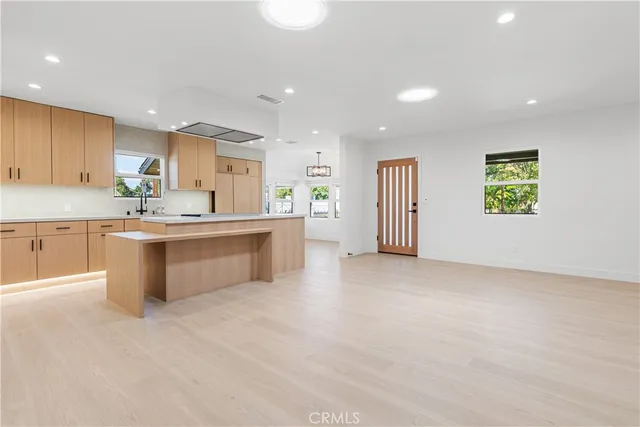 a large white kitchen with kitchen island a stove a sink a refrigerator and blue cabinets with wooden floor