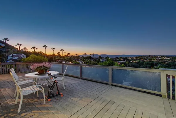 a view of a chairs and table on the wooden roof deck