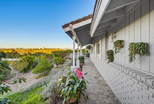 a view of a brick house with large trees and wooden fence