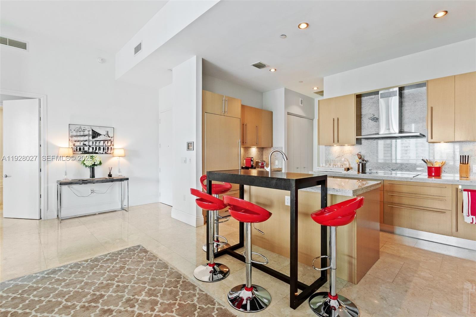 900 Brickell Key Boulevard, Unit 2002 Miami, FL 33131 - Photo 7 of 28 a kitchen with stainless steel appliances kitchen island granite countertop a dining table chairs sink and cabinets