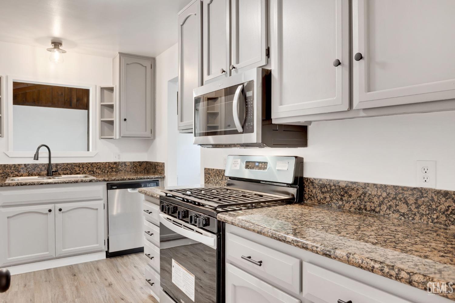 Undisclosed Address Bakersfield, CA 93312 - Photo 9 of 29 a kitchen with granite countertop cabinets stainless steel appliances and a wooden floor