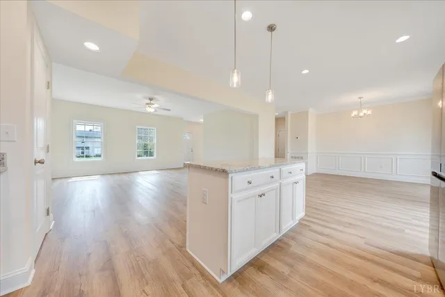a view of an empty room and kitchen with wooden floor