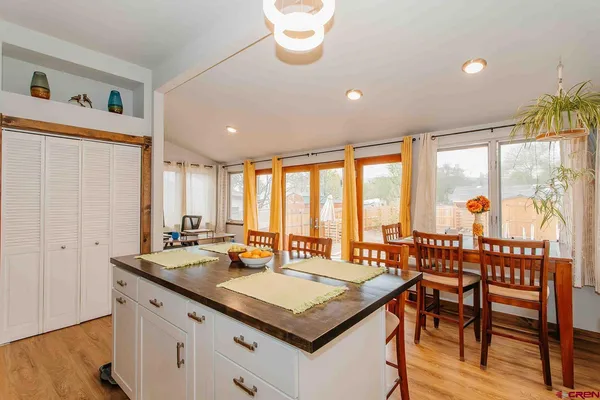 a kitchen with a stove a sink and a dining table with wooden floor