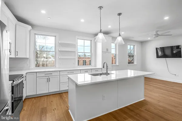 a large kitchen with kitchen island granite countertop a sink a counter space appliances and cabinets