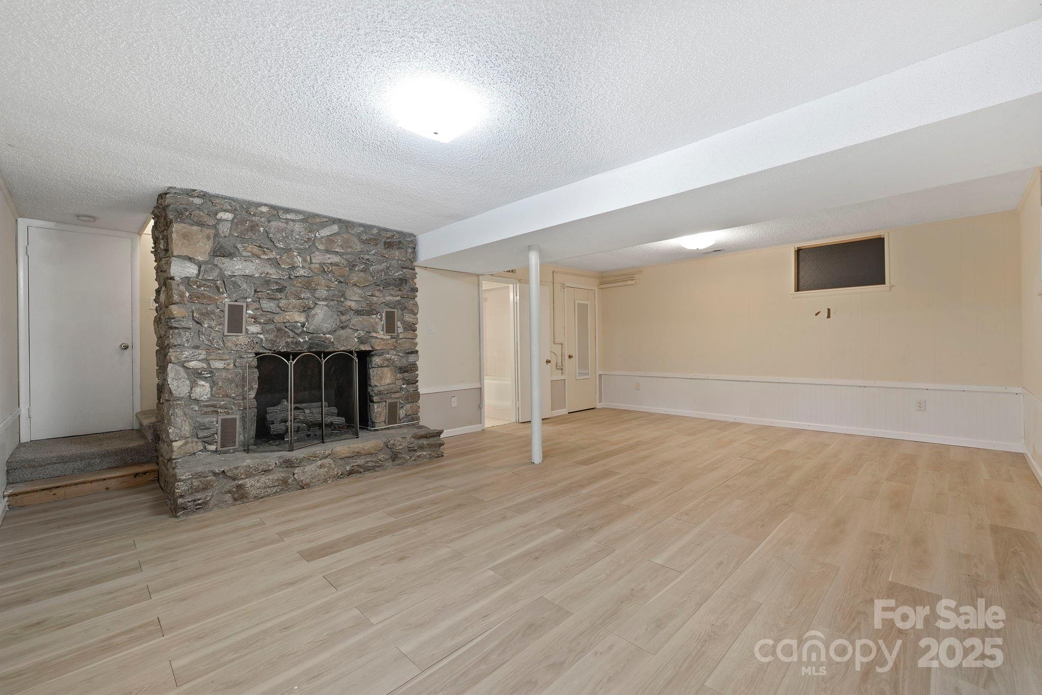 95 Temple Road Black Mountain, NC 28711 - Photo 18 of 30 an empty room with wooden floor and fireplace