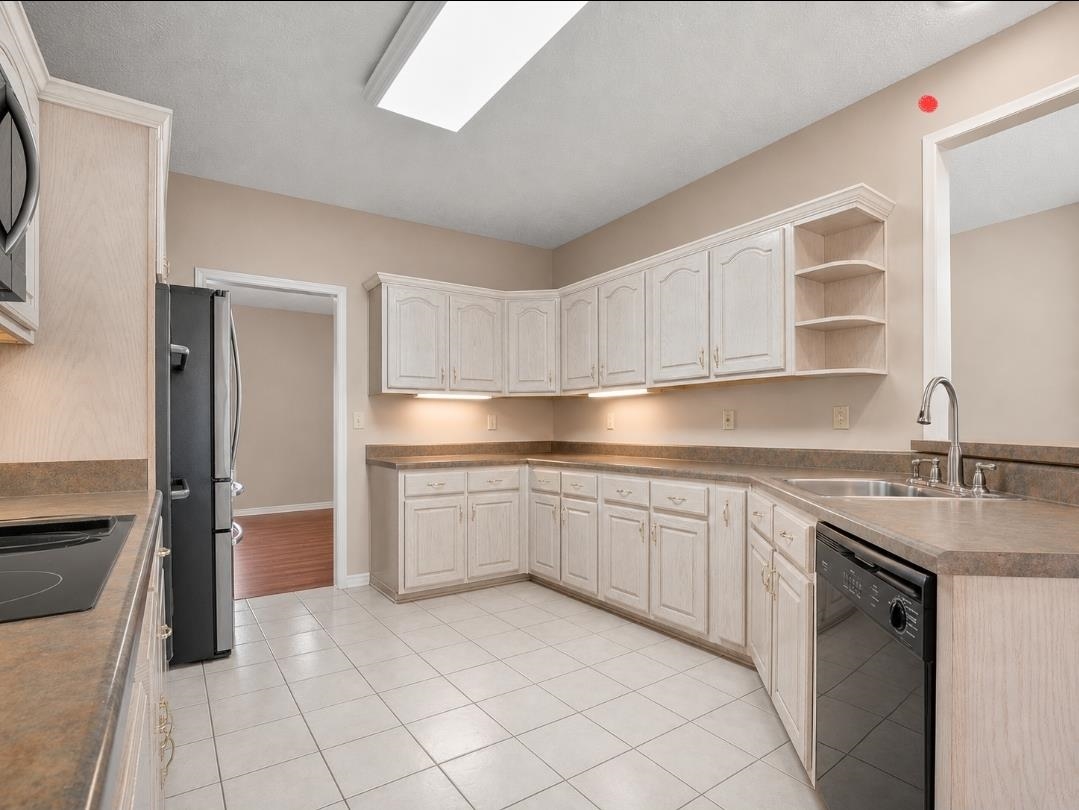 3779 Dancyville Road Stanton, TN 38069 - Photo 4 of 22 Kitchen featuring extensive light-toned cabinetry with under-cabinet lighting, a built-in black dishwasher, a stainless steel sink with a high-arc faucet, and tiled flooring