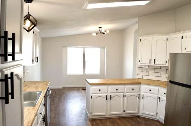 a kitchen with stainless steel appliances granite countertop a hardwood floor and a window