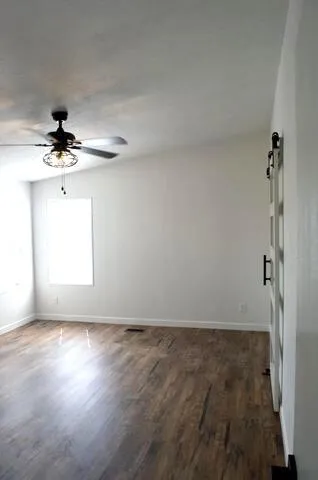 a view of an empty room with wooden floor and a window