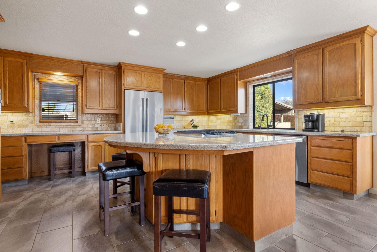 19909 Comstock Road Linden, CA 95236 - Photo 10 of 51 a kitchen with granite countertop wooden cabinets a stove a sink dishwasher and a refrigerator with wooden floor