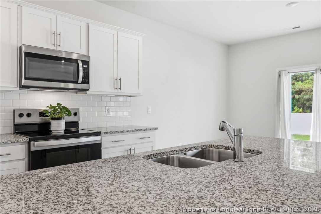 2208 Clydesmill Road Fayetteville, NC 28314 - Photo 11 of 26 a kitchen with granite countertop a sink and a stove top oven