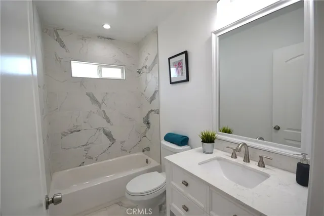 a bathroom with a bathtub shower sink vanity mirror and toilet