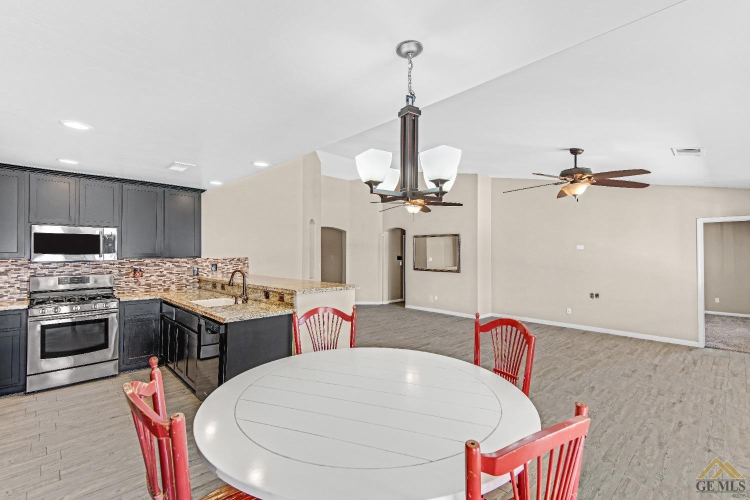 Undisclosed Address Bakersfield, CA 93312 - Photo 12 of 31 a kitchen with stainless steel appliances kitchen island granite countertop a sink a stove and a wooden floors