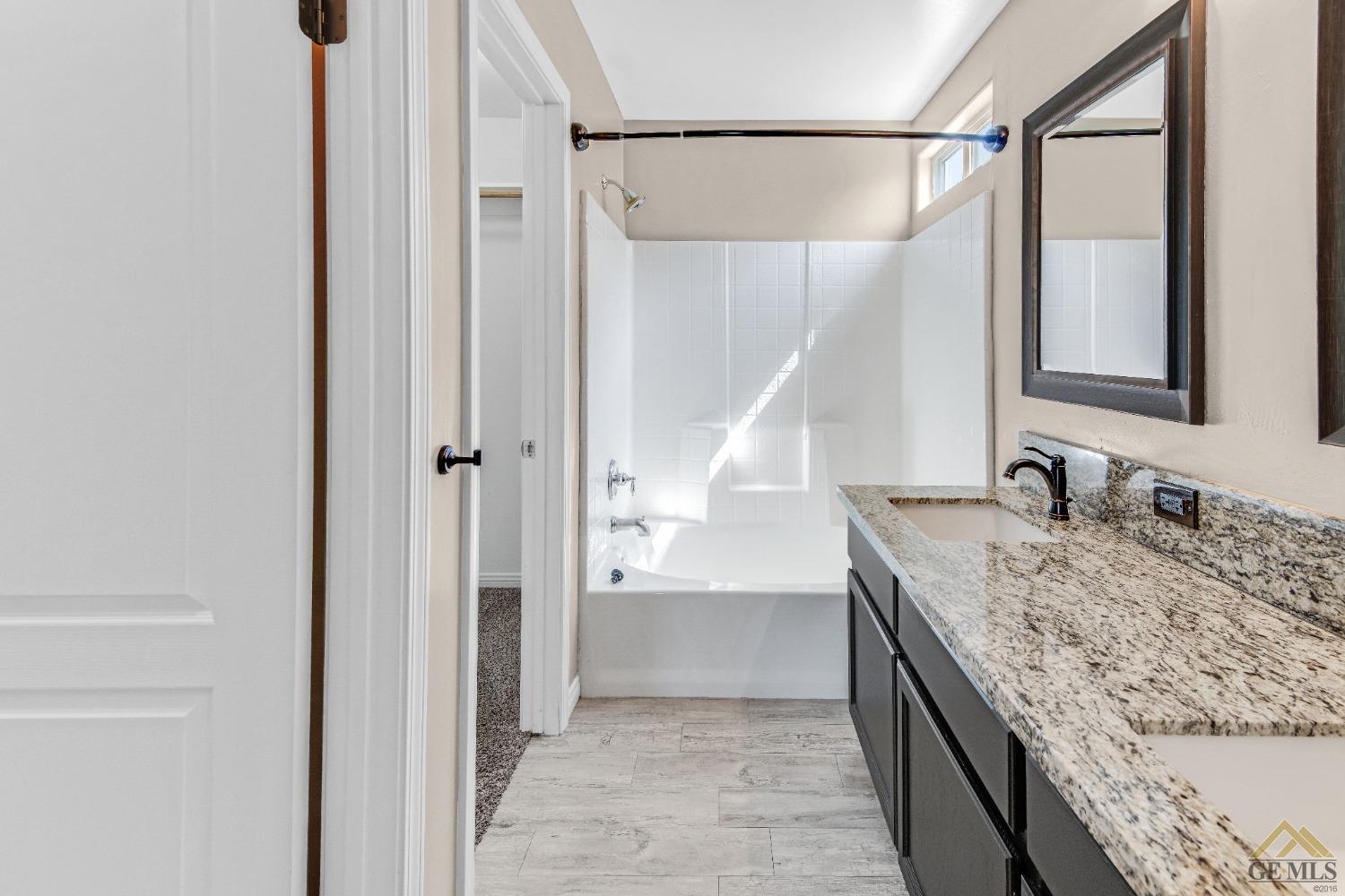 Undisclosed Address Bakersfield, CA 93312 - Photo 15 of 31 a bathroom with a granite countertop sink a mirror and shower