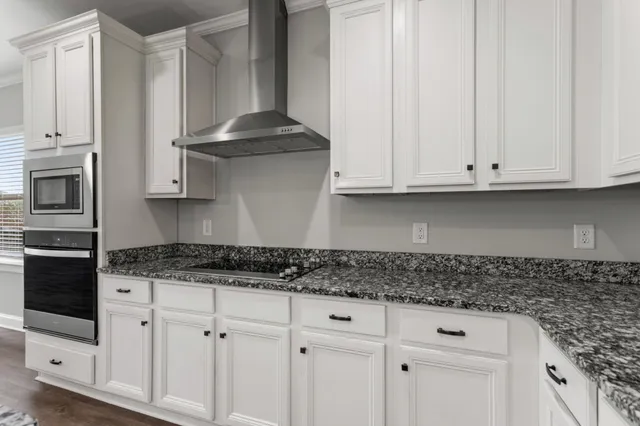 a kitchen with stainless steel appliances granite countertop white cabinets sink and a granite counter top