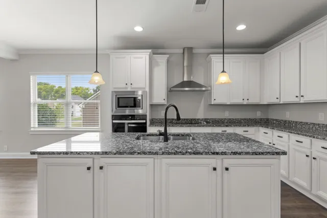 a kitchen with stainless steel appliances granite countertop a sink a stove and a wooden floor