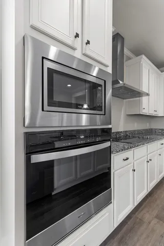 a kitchen with granite countertop white cabinets and stainless steel appliances