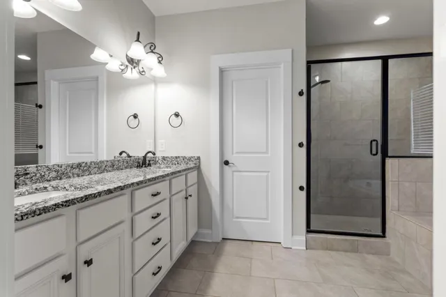 a spacious bathroom with a granite countertop sink a mirror and shower