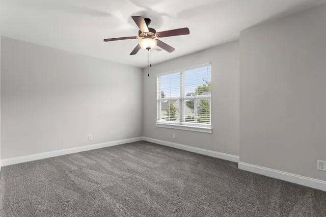 an empty room with ceiling fan and windows