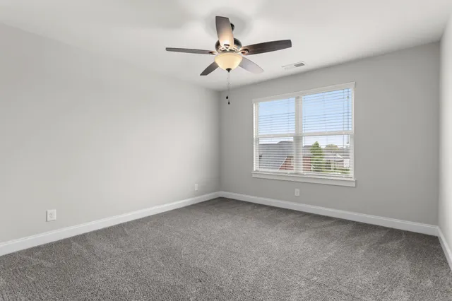 an empty room with a window and a ceiling fan