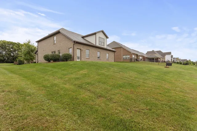 a view of a big house with a big yard and a large tree