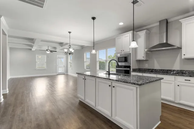 a kitchen with granite countertop a stove a sink a center island and wooden floor