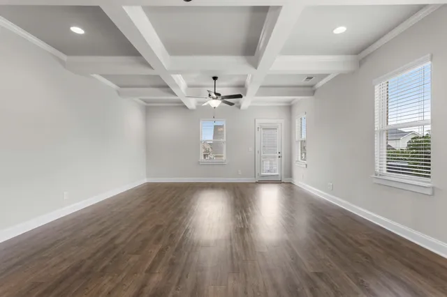 an empty room with wooden floor ceiling fan and windows